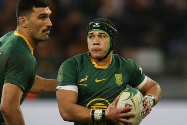 Springboks wing Cheslin Kolbe carries the ball in green and gold, watched by a team-mate