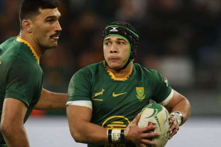 Springboks wing Cheslin Kolbe carries the ball in green and gold, watched by a team-mate