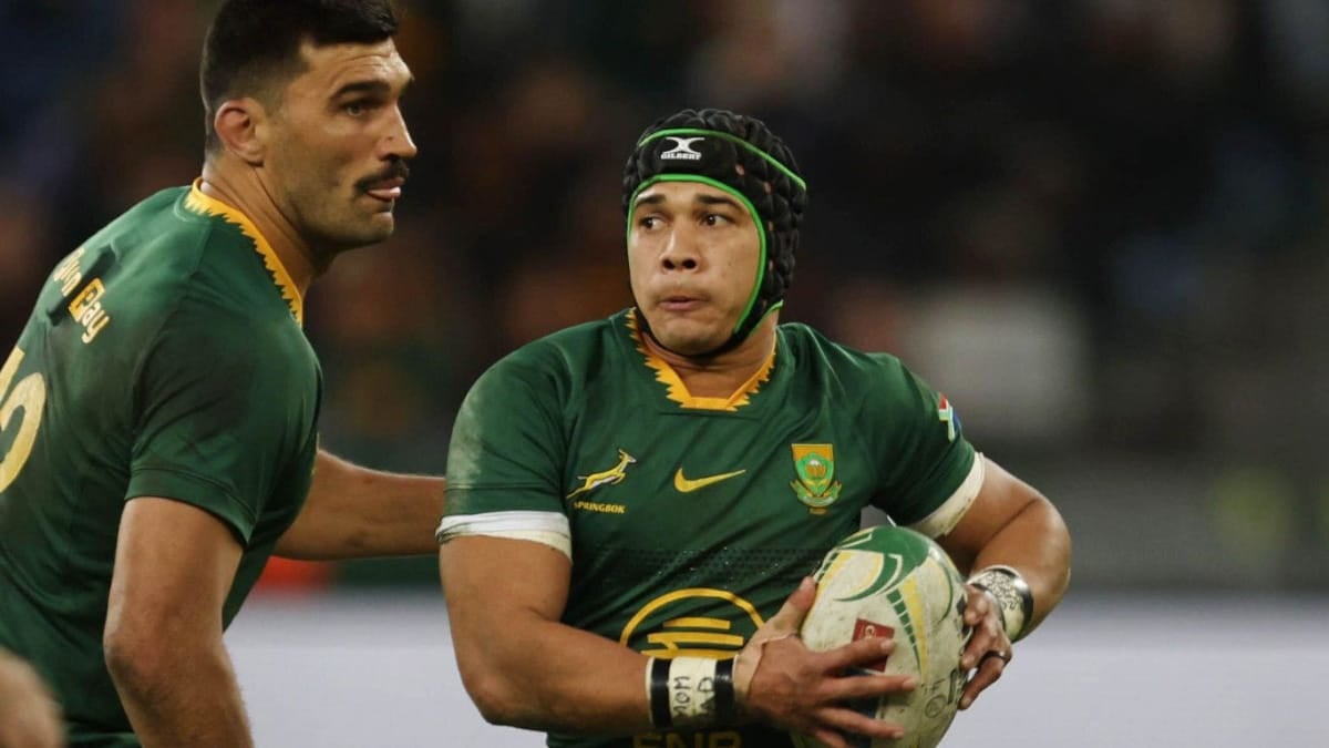Springboks wing Cheslin Kolbe carries the ball in green and gold, watched by a team-mate