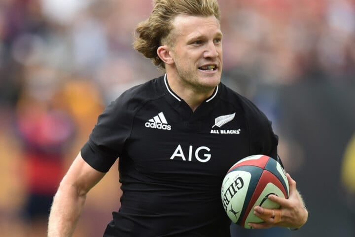 Damian McKenzie running with the ball in an All Blacks jersey