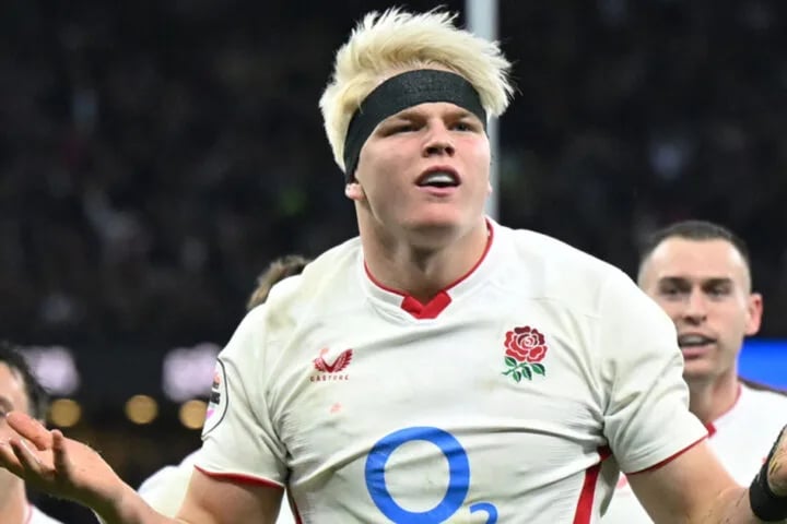 Henry Pollock celebrating with his arms spread in an England shirt during a night Test match