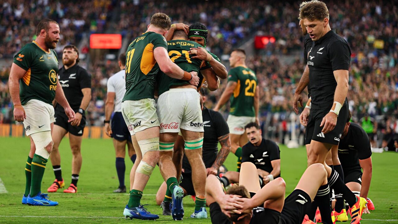 Springboks players celebrate a try in Baltimore while All Blacks lie on the turf and Beauden Barrett walks away