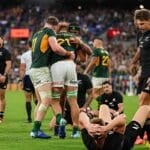 Springboks players celebrate a try in Baltimore while All Blacks lie on the turf and Beauden Barrett walks away