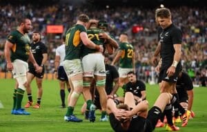 Springboks players celebrate a try in Baltimore while All Blacks lie on the turf and Beauden Barrett walks away