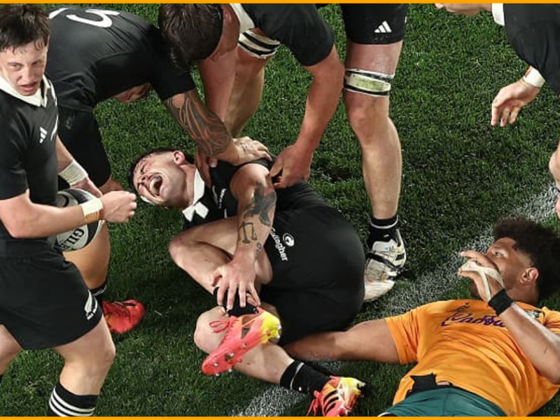 Leroy Carter holds his ankle on the Eden Park turf as All Blacks teammates stand over him and a Wallabies player lies beside him