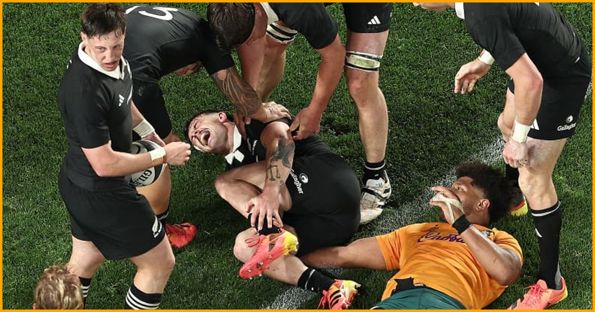 Leroy Carter holds his ankle on the Eden Park turf as All Blacks teammates stand over him and a Wallabies player lies beside him